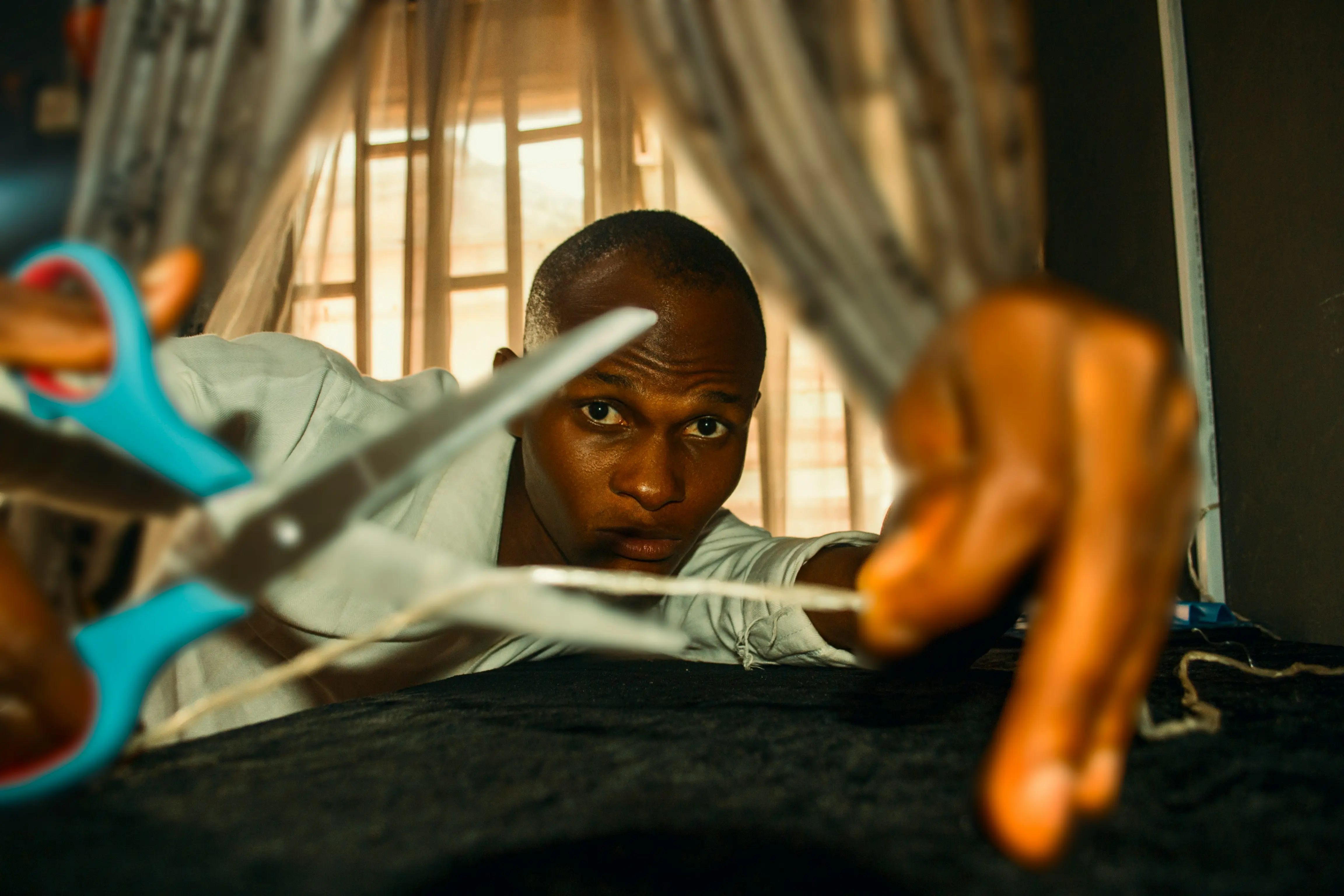 Artisan Kenyan cousant un patch de tissu wax sur un t-shirt.